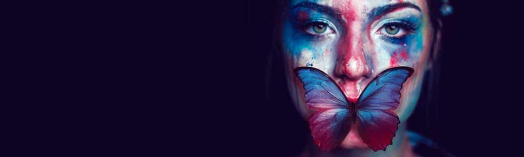Femme au visage peint et papillon sur sa bouche